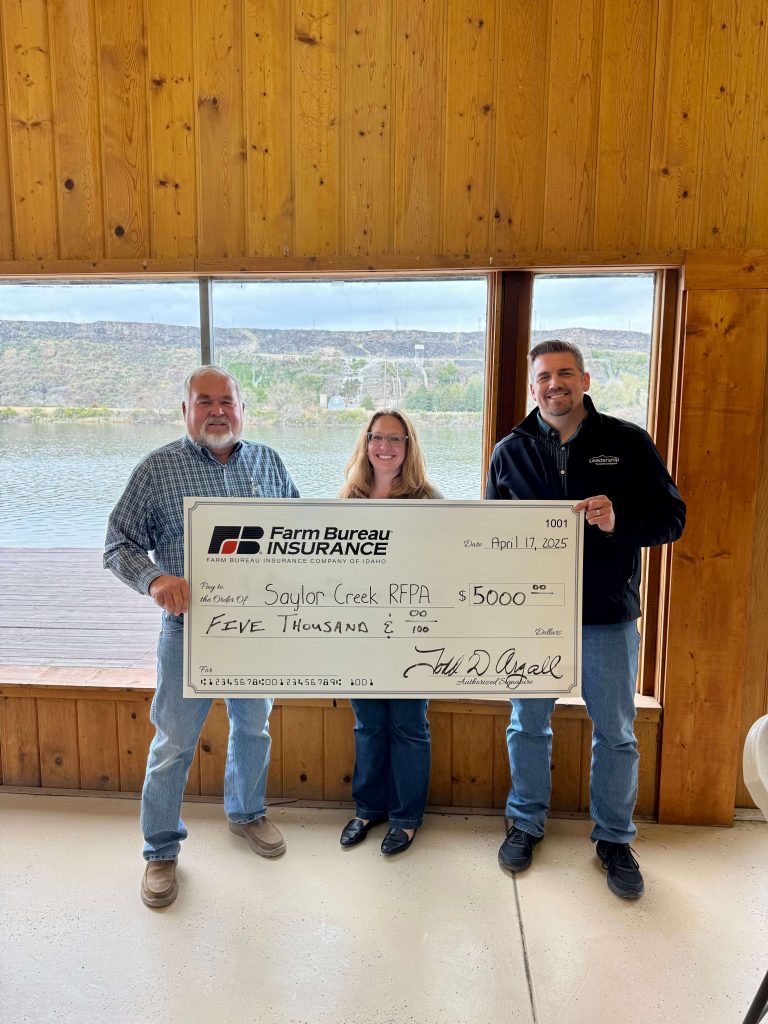 Farm Bureau Insurance Company of Idaho agent Jade Sparrow and Director of Customer Experience and Marketing Dana May present a $5,000 check to the Saylor Creek RFPA during a volunteer training session.
