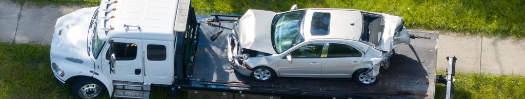 Car crash site with tow truck loading destroyed vehicle